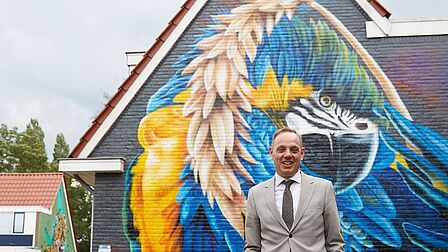 Burgemeester Ron König voor een muurschildering in Sluiswijk
