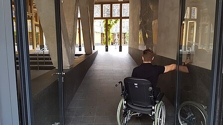 Iemand in een rolstoep bij de ingang van het stadhuis