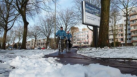 Mensen die fietsen over een fietspad dat sneeuwvrij is gemaakt